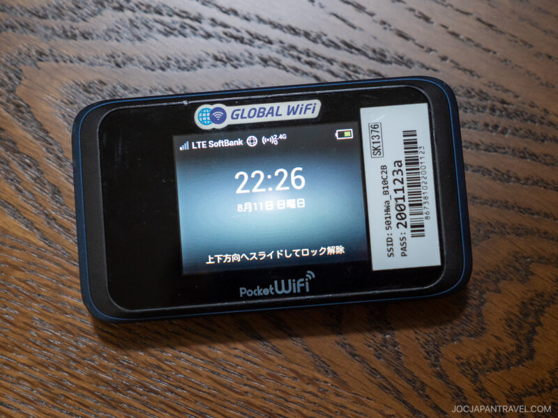 A Japan Wifi portable device rests on a wooden surface, displaying the time 22:26 on its screen with LTE SoftBank signal indicators and a barcode sticker on the top right corner.