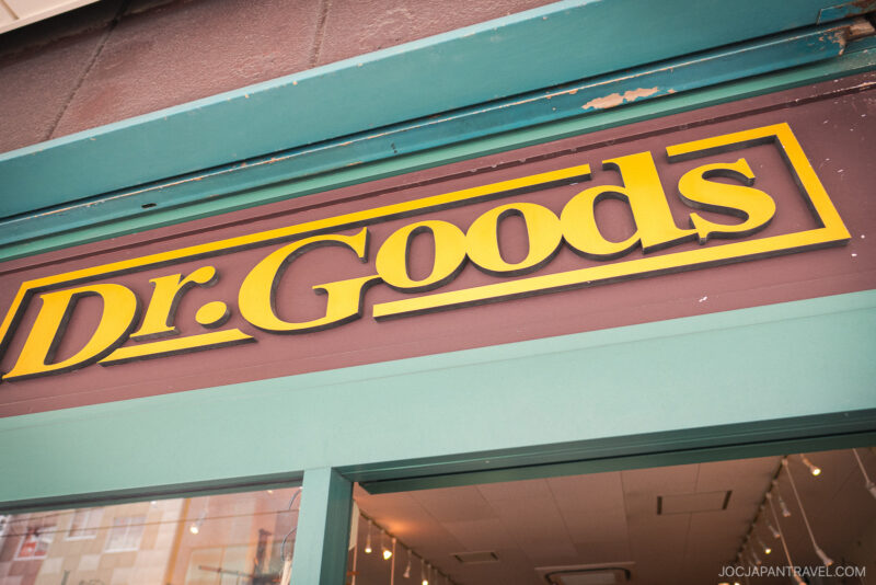 A store sign with bold yellow text reading “Dr. Goods” on a brown background sits above the teal-colored Kappabashi Dr. Goods storefront.