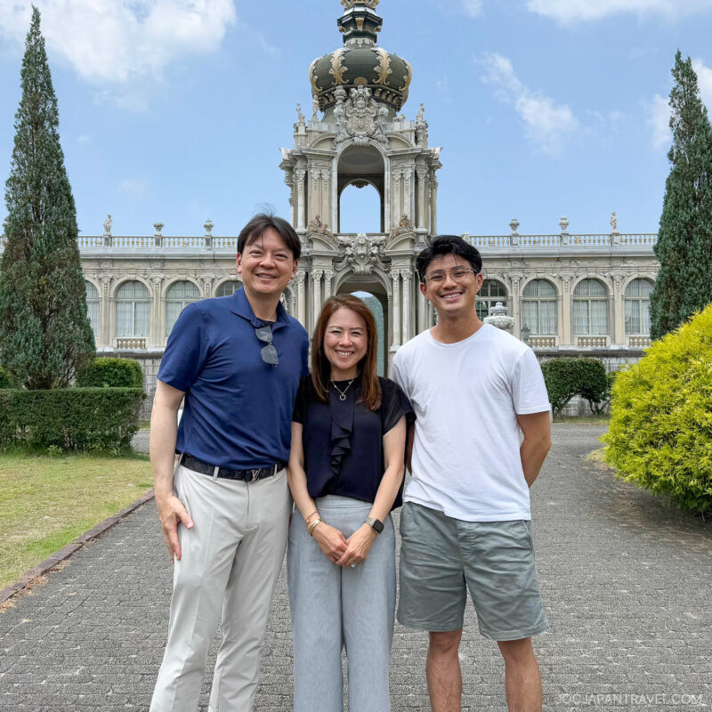 Three people stand smiling in front of the ornate Crown Gate at Dresden’s Zwinger Palace, sharing their love for culture on a sunny day, with lush greenery and a clear blue sky in the background.